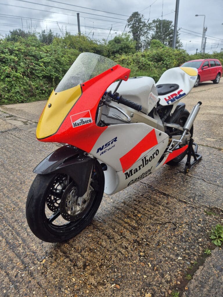 Classic red and white racing motorcycle parked outdoors.