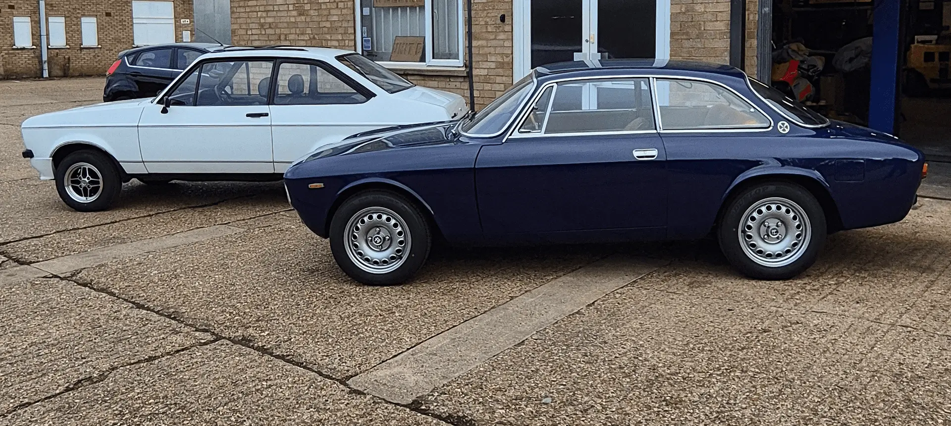 A classic dark blue vintage car parked on a driveway.
