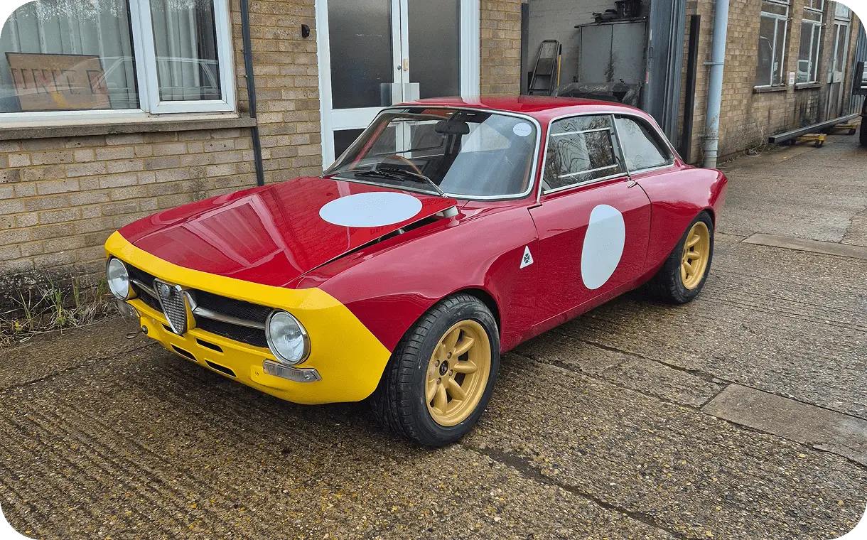 Classic red and yellow vintage race car with white roundels parked outside.